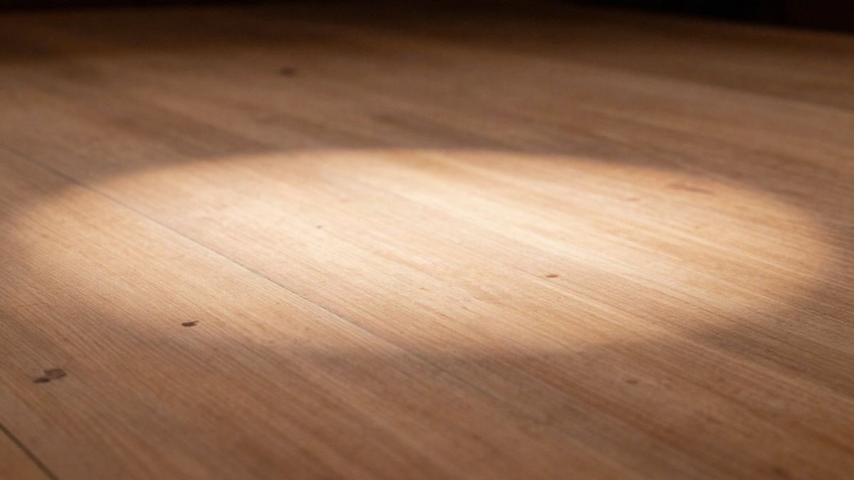 Imagen ilustrativa: detalle de un suelo de madera de escenario con un foco de luz teatral