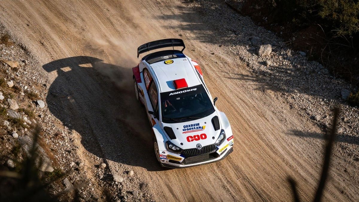 Imagen ilustrativa: vista cenital de un coche de rally en un camino de montaña con polvo y luz de atardecer