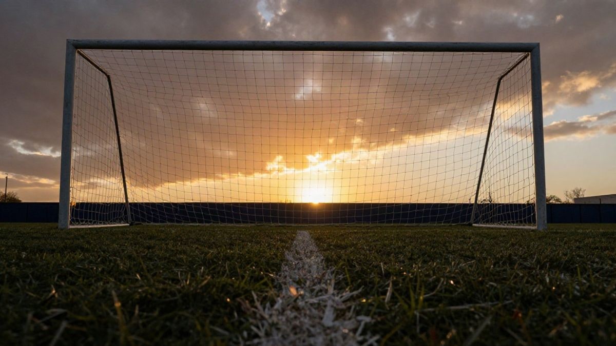 Imagen ilustrativa: ángulo bajo de una portería de fútbol con la red recortada contra el cielo al atardecer
