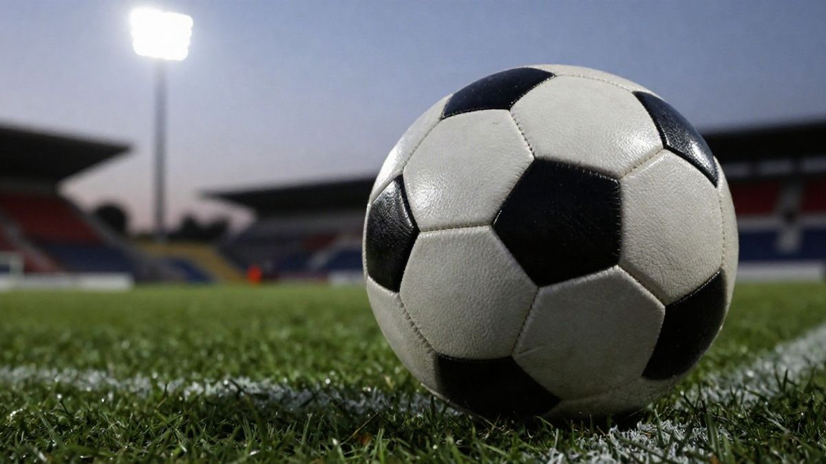 Imagen ilustrativa: balón de fútbol sobre la hierba de un estadio al atardecer, con focos desenfocados al fondo