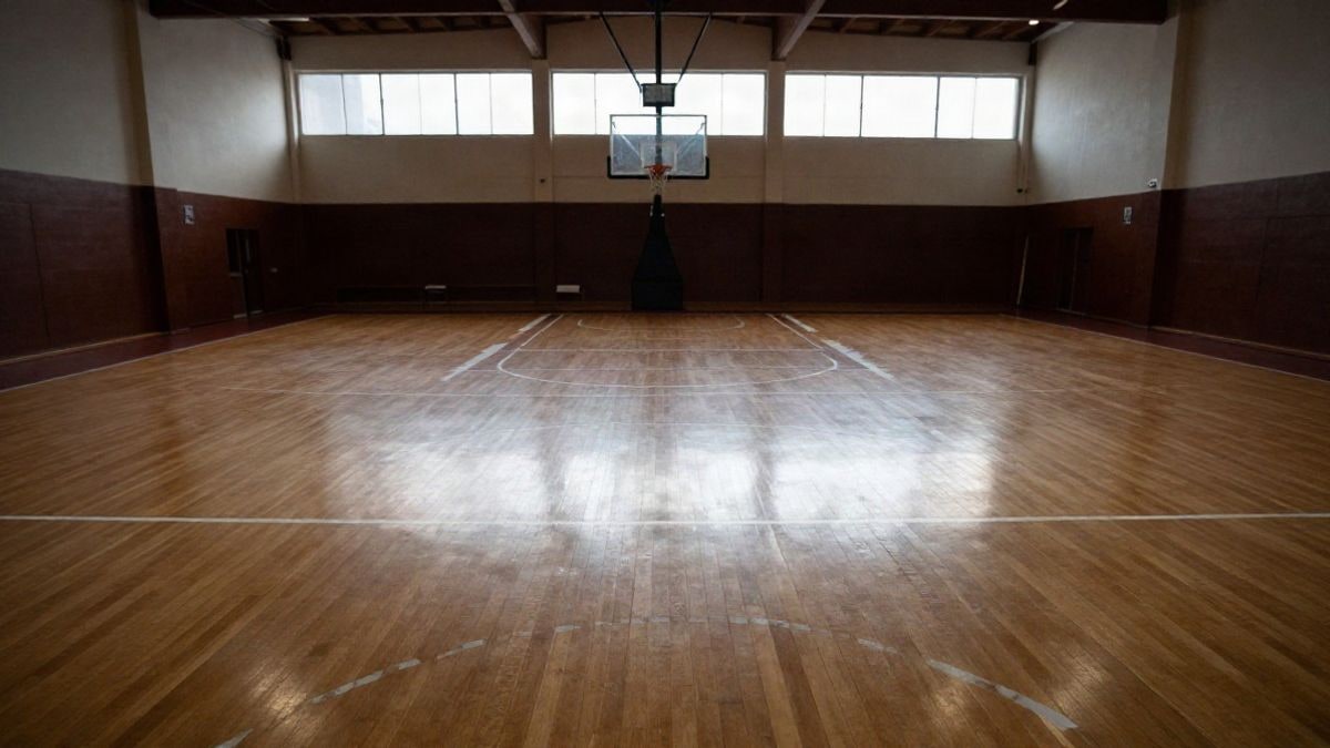 Imagen ilustrativa: cancha de baloncesto cubierta vacía con líneas que convergen hacia una canasta