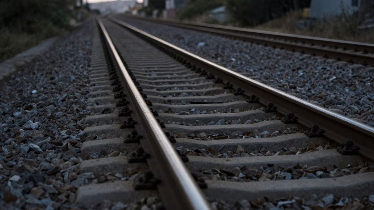 Imagen ilustrativa: vía ferroviaria que se pierde en la distancia al atardecer, con sombras largas sobre la grava y los railes