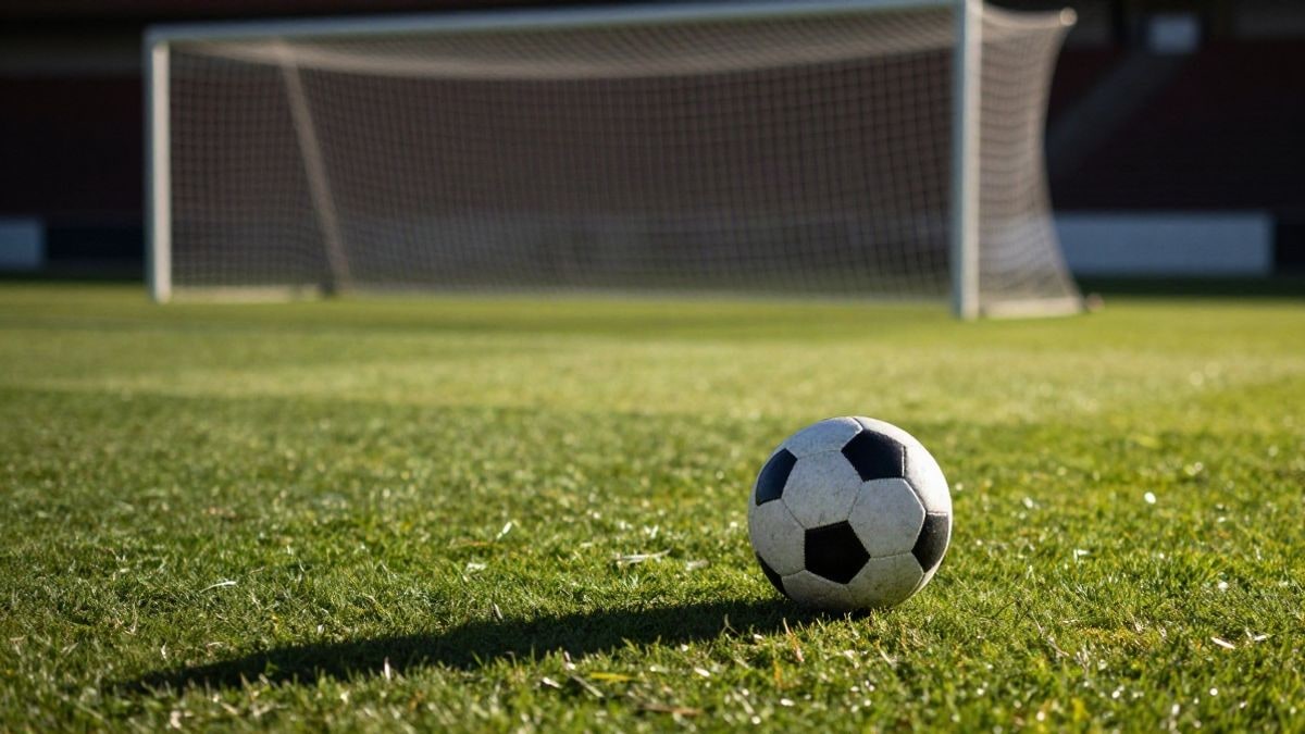 Imagen ilustrativa: un balón de fútbol sobre el césped de un estadio al atardecer, con la red de la portería al fondo.