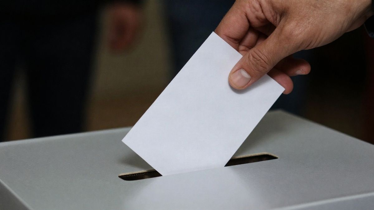 Imagen ilustrativa: una mano depositando una papeleta en una urna electoral, sin rostros visibles