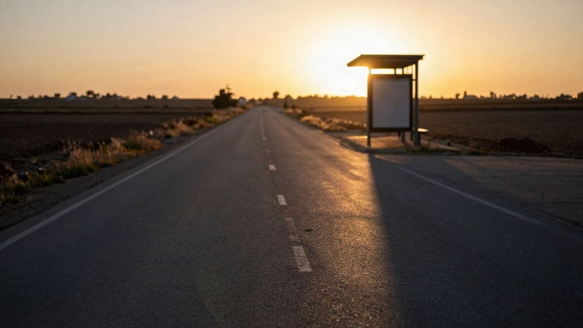 Imagen ilustrativa: carretera rural vacía al atardecer, con sombras largas y una parada cubierta recortada al contraluz