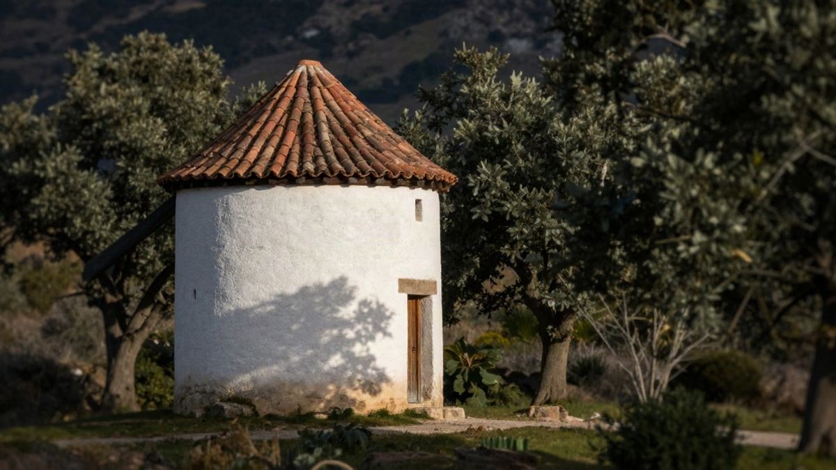 Imagen ilustrativa: edificio rural de piedra y teja junto a árboles y jardines al atardecer