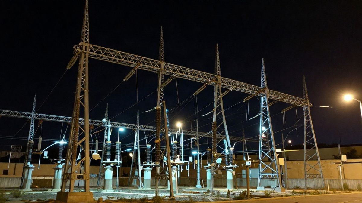 Imagen ilustrativa: torres de alta tensión iluminadas de noche junto a una subestación eléctrica