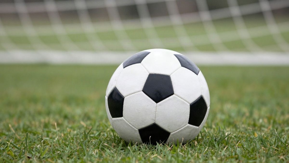 Imagen ilustrativa: balón de fútbol sobre césped con portería al fondo