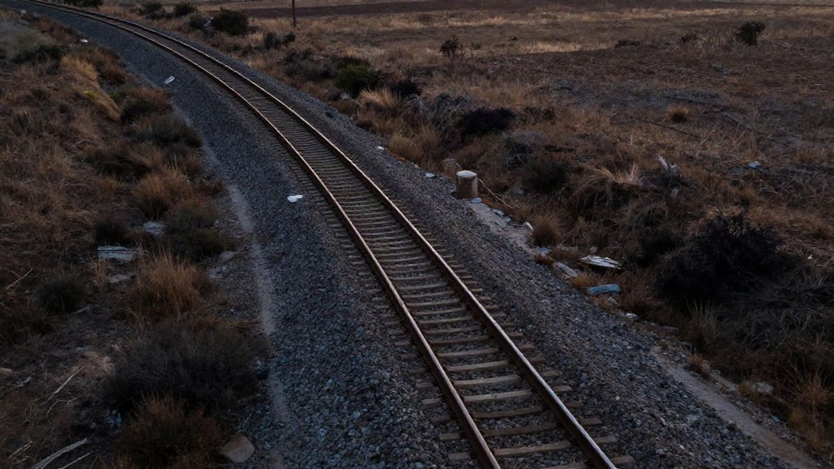 Imagen ilustrativa: vía de ferrocarril vista desde arriba al atardecer, con balasto y luz rasante sobre una llanura seca
