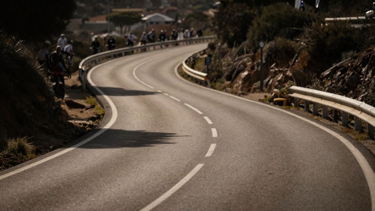 Imagen ilustrativa: carretera costera con líneas convergentes durante una carrera ciclista al atardecer