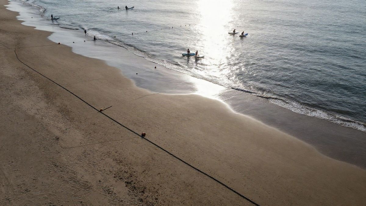 Imagen ilustrativa: vista aérea de una playa con boyas de competición en el agua y palistas de paddle surf en la distancia