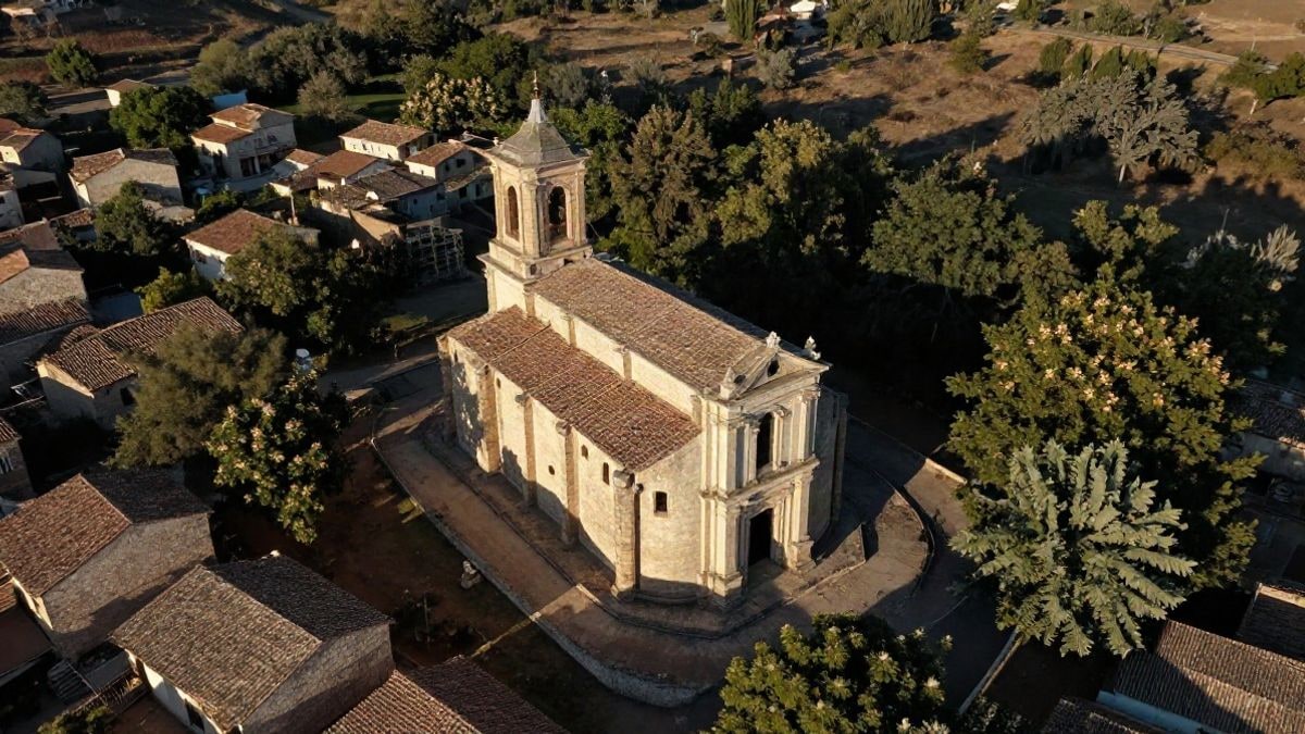 Imagen ilustrativa: vista cenital de un pueblo serrano con una gran iglesia inacabada rodeada de castaños