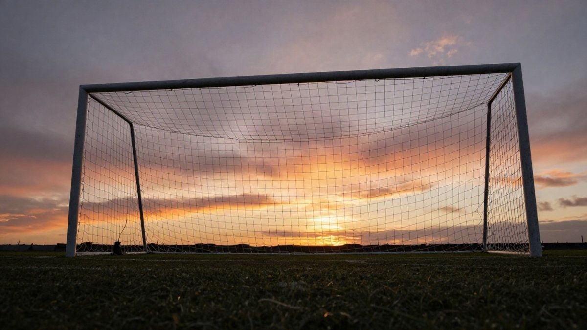 Imagen ilustrativa: ángulo bajo de una portería de fútbol con la red recortada contra el cielo al atardecer