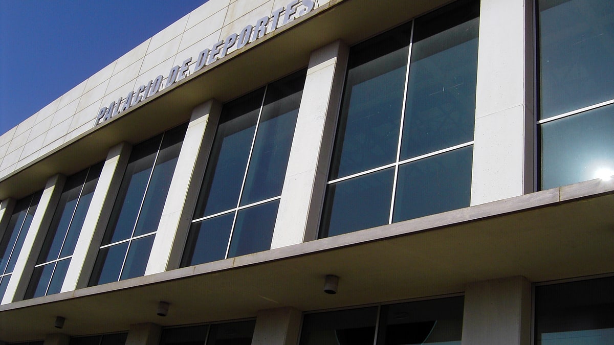 Fachada exterior del Palacio de Deportes de Huelva con grandes ventanales y letras en la cornisa.