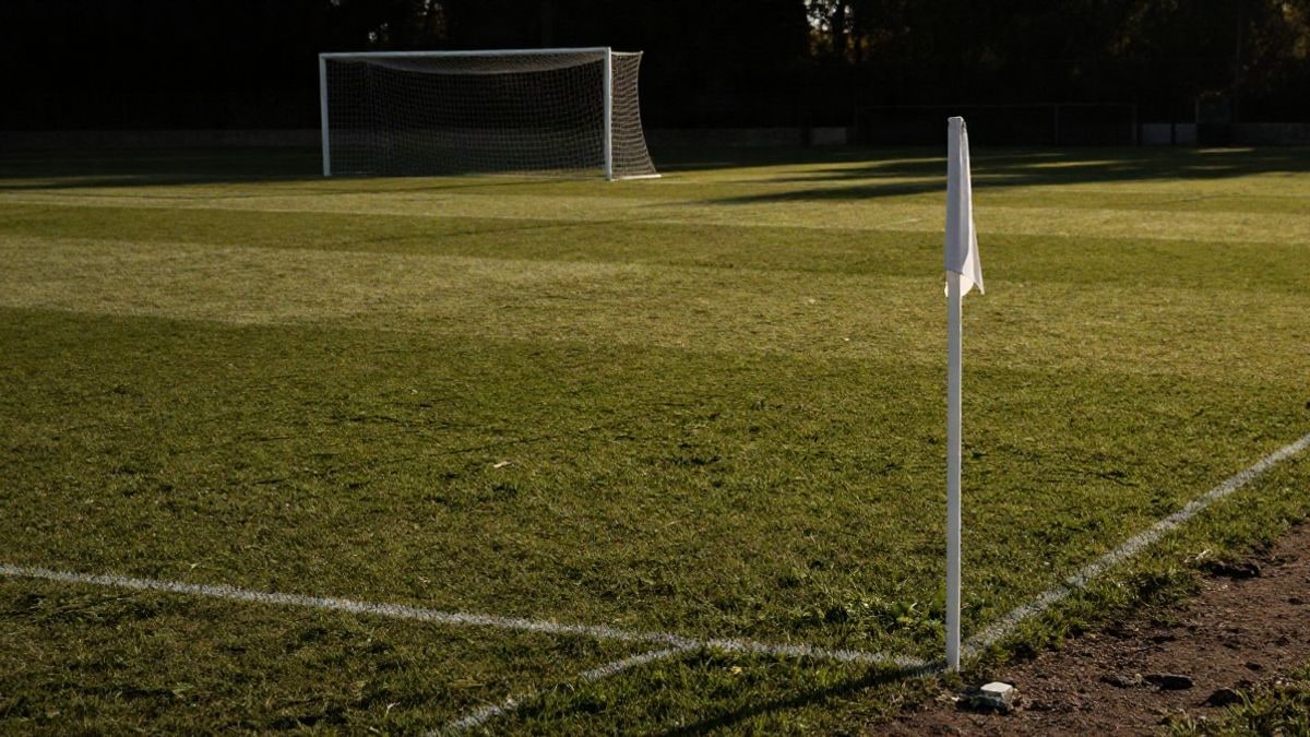 Imagen ilustrativa: campo de fútbol base al atardecer con la portería al fondo y líneas del campo convergiendo