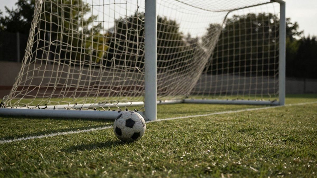 Imagen ilustrativa: detalle de una portería de fútbol con el balón sobre el césped