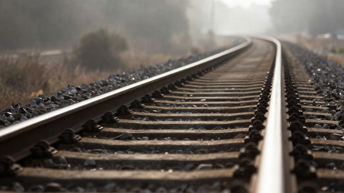 Imagen ilustrativa: vías de tren vacías que se pierden entre la niebla de la mañana, con traviesas de madera en primer plano