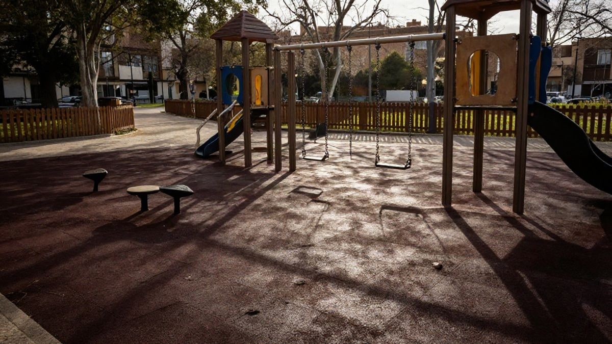 Imagen ilustrativa: zona infantil renovada con columpios y suelo de caucho en un parque urbano