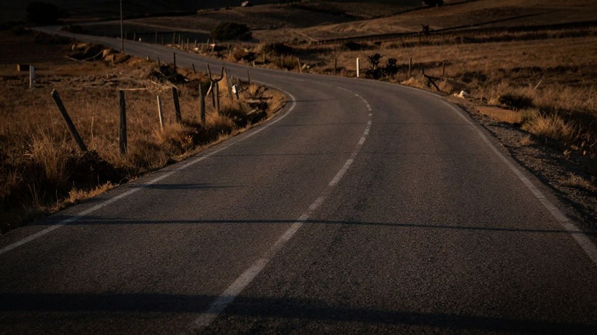 Imagen ilustrativa: una carretera rural española al atardecer, con una valla de madera junto al arcén