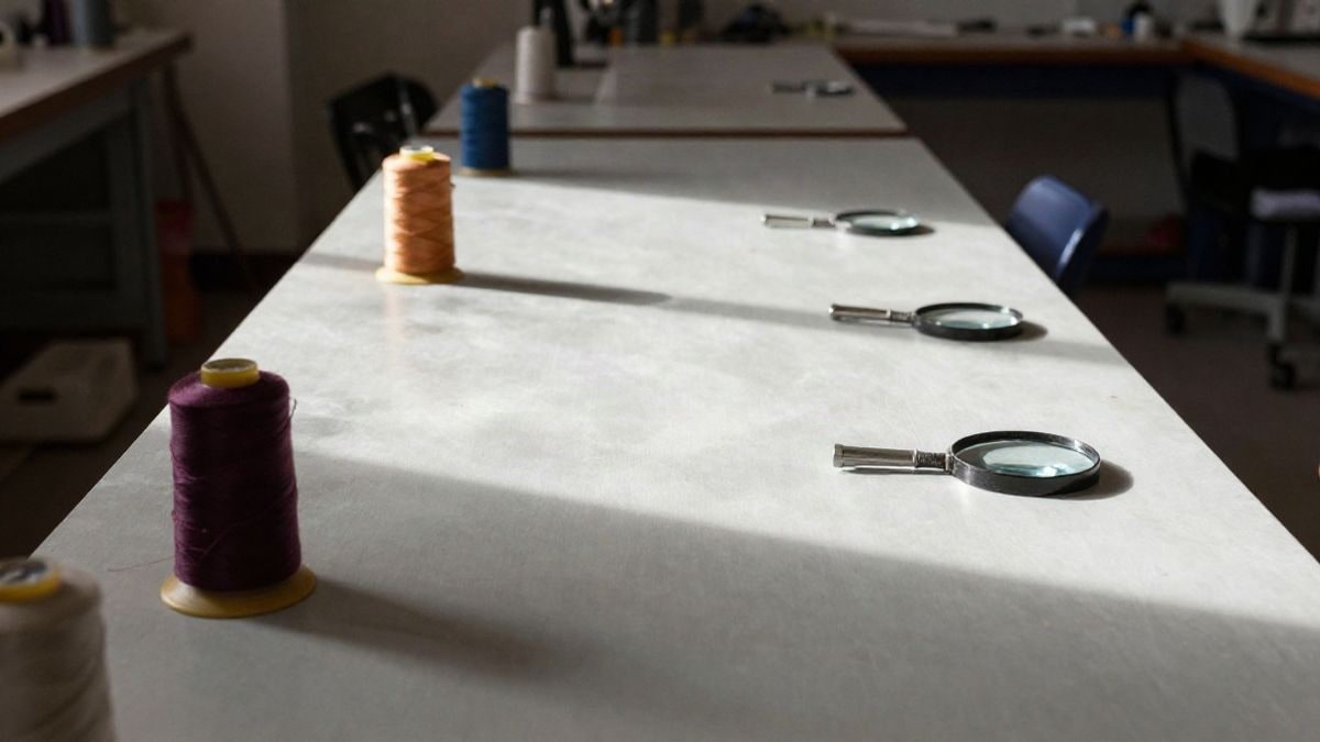 Imagen ilustrativa: taller de restauración textil con herramientas y lupa sobre una mesa