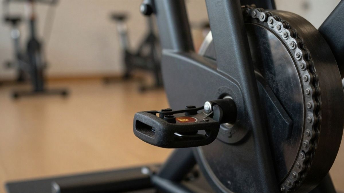 Imagen ilustrativa: primer plano macro del mecanismo de una bicicleta estática en un pabellón deportivo