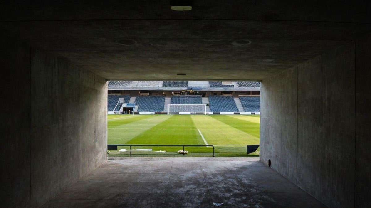Imagen ilustrativa: túnel de un estadio de fútbol vacío con el césped y la portería al fondo
