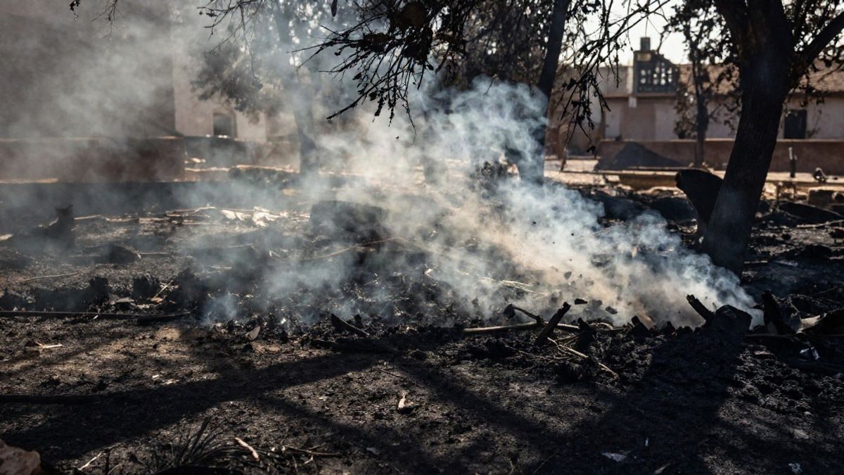 Imagen ilustrativa: un asentamiento de chabolas con restos quemados y humo al amanecer