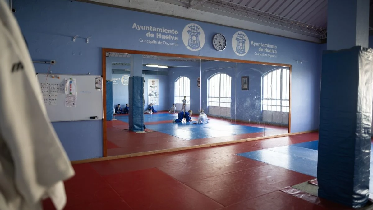 Imagen ilustrativa: interior de un gimnasio municipal vacío con conductos de ventilación en el techo y luz natural