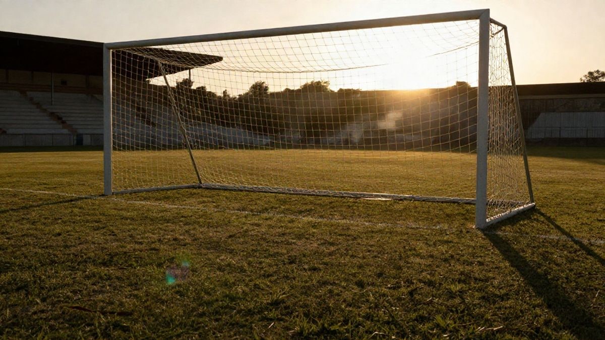 Imagen ilustrativa: portería de fútbol a contraluz al atardecer con sombras largas sobre el césped