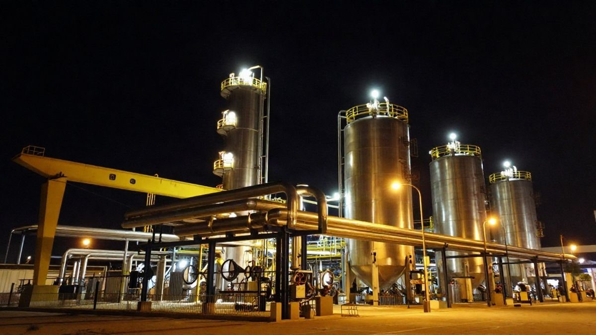 Imagen ilustrativa: tuberías y depósitos industriales iluminados de noche en una instalación energética