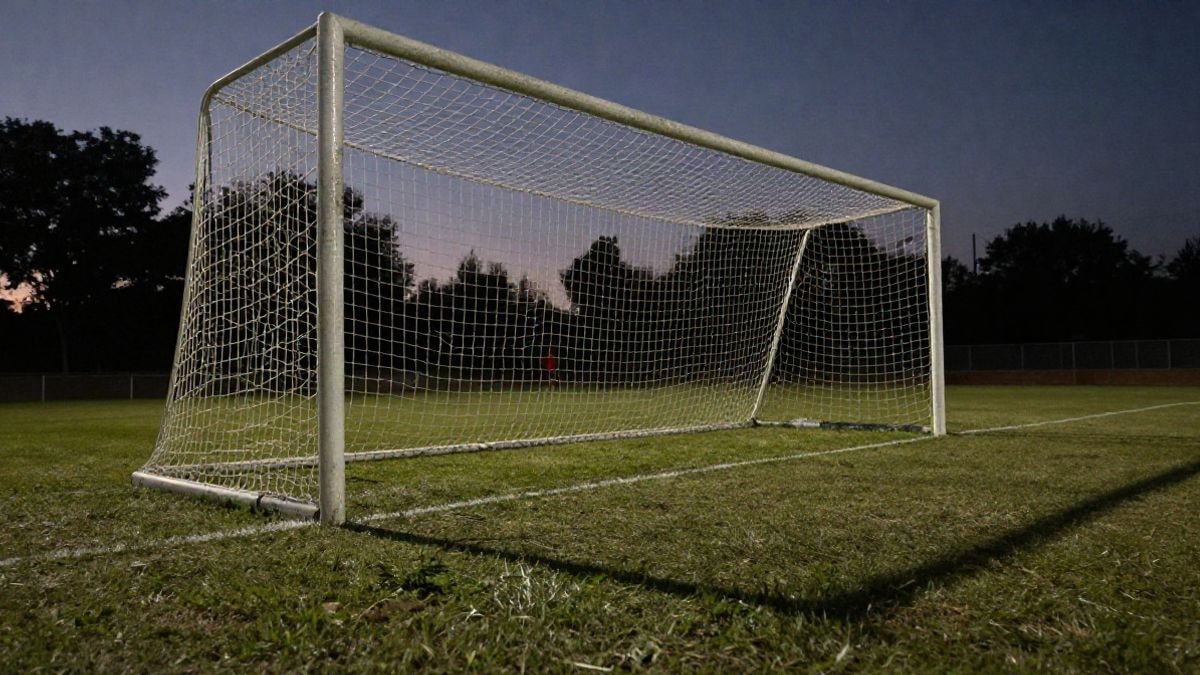Imagen ilustrativa: portería de fútbol vacía con red, vista desde un ángulo bajo al atardecer
