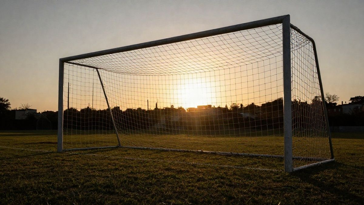 Imagen ilustrativa: portería de fútbol con la red recortada a contraluz al atardecer, con sombras largas sobre el césped