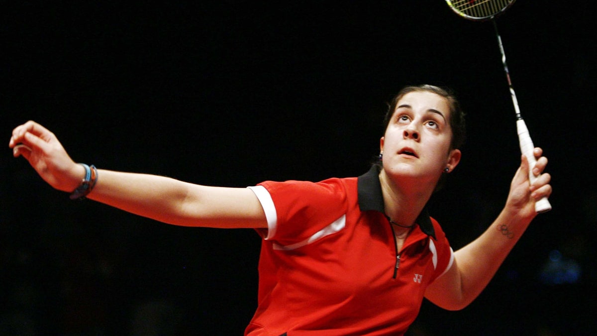 Carolina Marín golpea con la raqueta en alto durante un partido de bádminton sobre fondo oscuro.