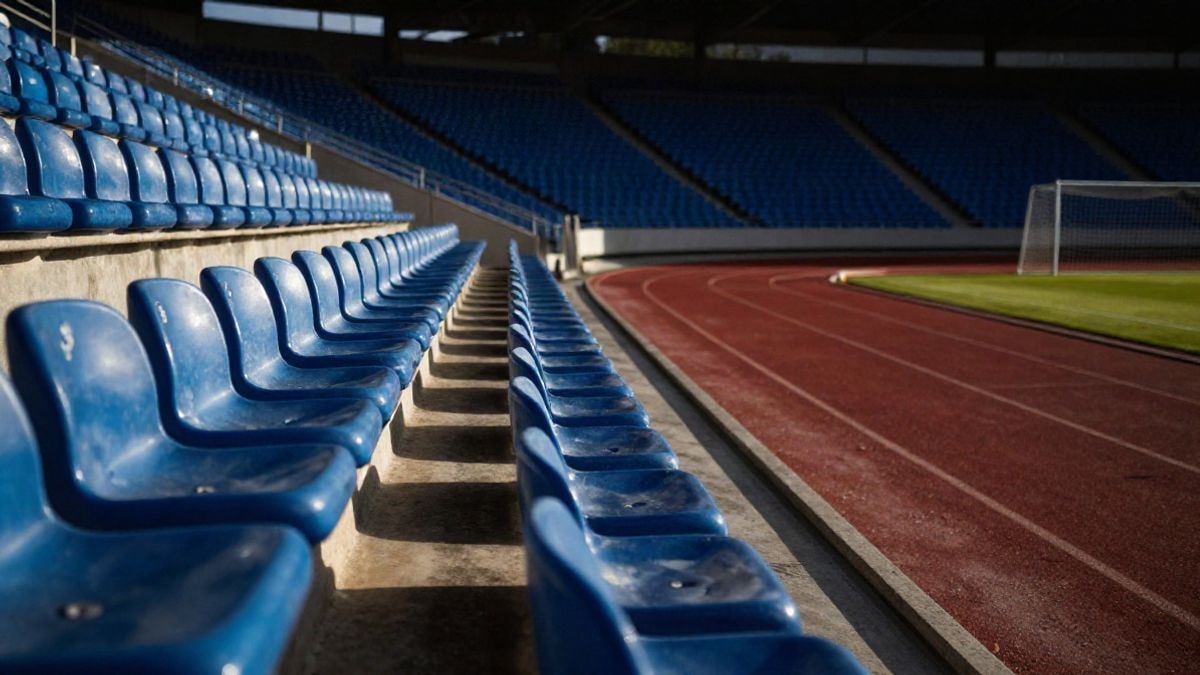 Imagen ilustrativa: ángulo bajo de una grada de estadio de fútbol vacía con asientos y luz de atardecer
