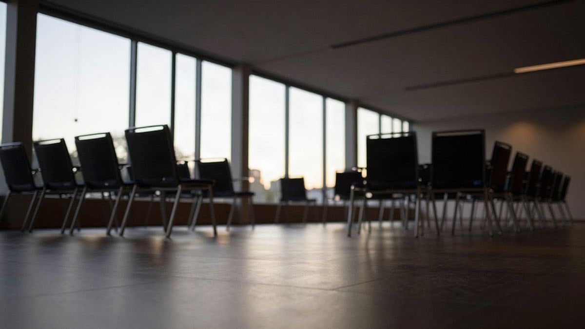Imagen ilustrativa: sala de conferencias moderna con sillas vacías frente a un escenario iluminado