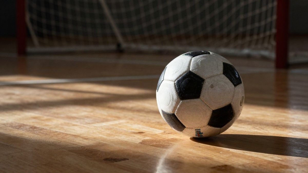 Imagen ilustrativa: balón de fútbol sala sobre pista de madera con portería al fondo
