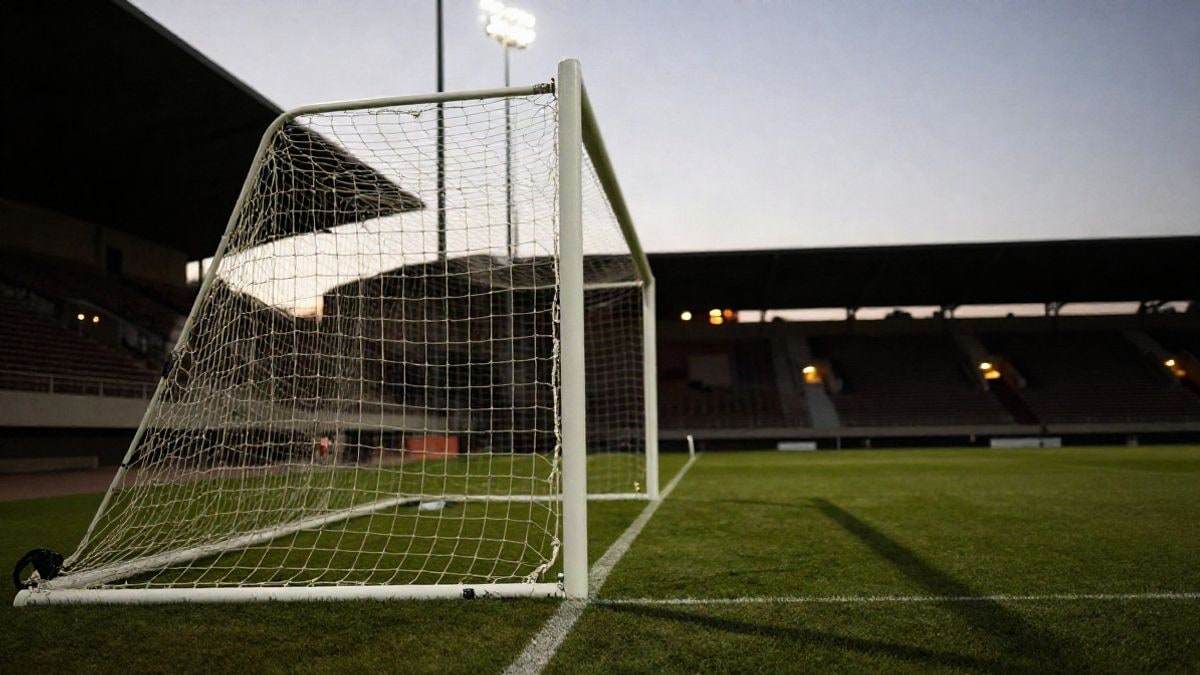 Imagen ilustrativa: portería de fútbol con la red vista de lado y luces de estadio desenfocadas al atardecer