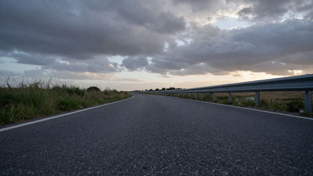 Imagen ilustrativa: carretera rural vista desde el suelo al atardecer, con cielo dramático de fondo