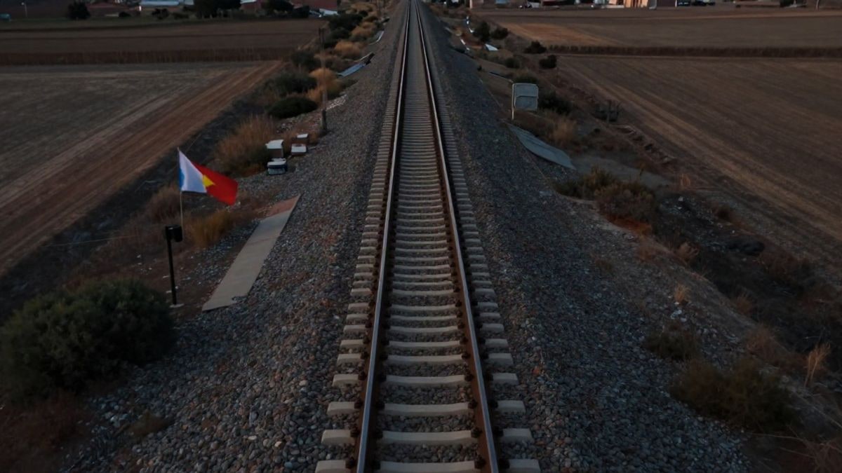 Imagen ilustrativa: vía de ferrocarril vista desde arriba atravesando una llanura seca al atardecer