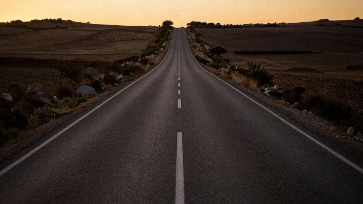 Imagen ilustrativa: una carretera rural de Andalucía que se pierde en el horizonte al atardecer, con sombras largas