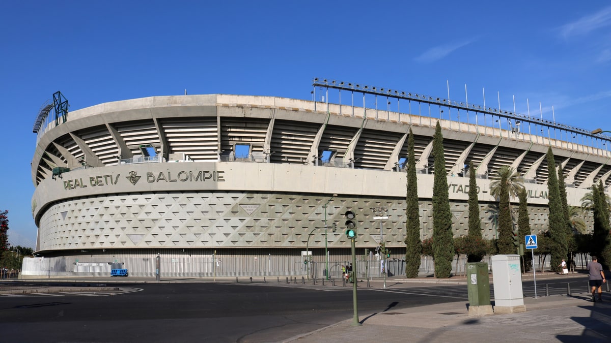 Fachada exterior del estadio Benito Villamarín con cielo azul y tráfico en primer plano