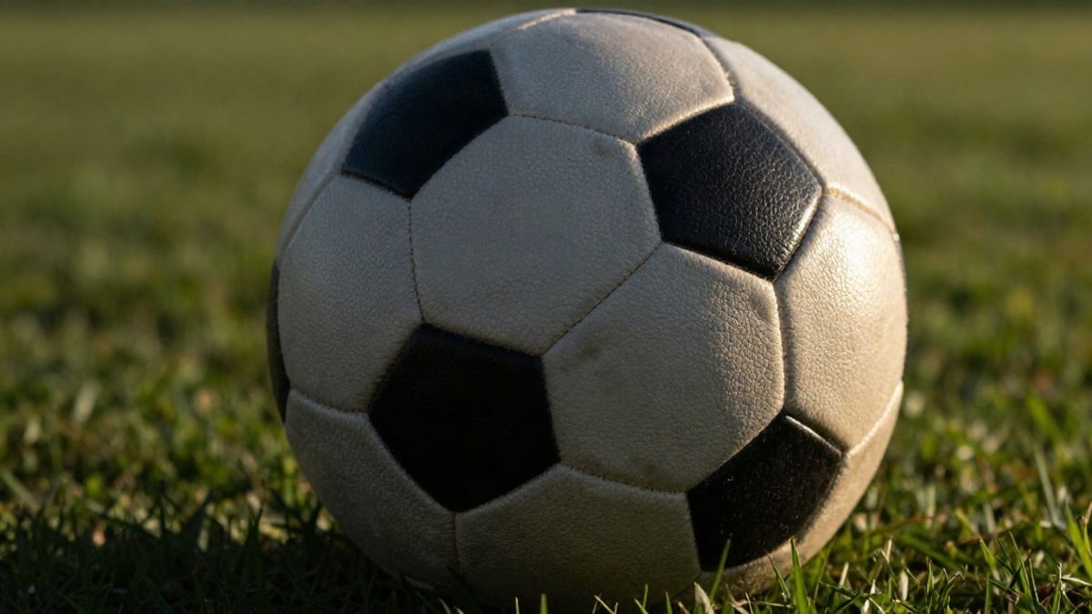 Imagen ilustrativa: primer plano macro de un balón de fútbol sobre el césped con luz de atardecer