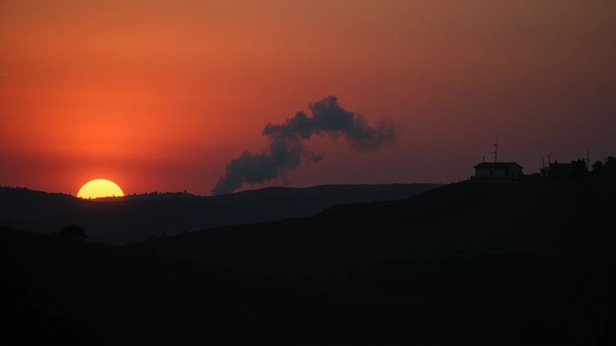 Imagen ilustrativa: un pueblo rural al atardecer con una columna de humo en el horizonte, siluetas y sombras largas.