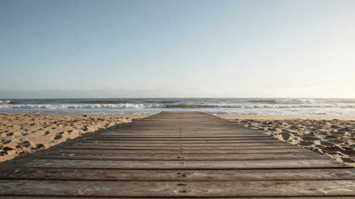 Imagen ilustrativa: paseo de madera sobre una playa tranquila con cielo despejado al fondo