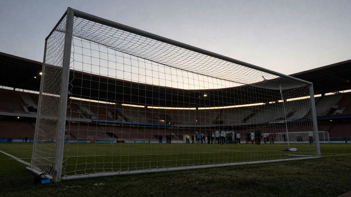 Imagen ilustrativa: portería de fútbol con la red a contraluz al atardecer, vista desde el campo con el punto de penalti en primer plano