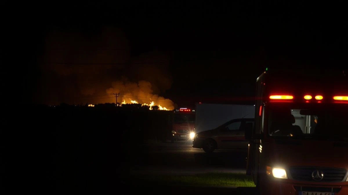 Imagen ilustrativa: vista nocturna de un incendio forestal con maquinaria pesada y vehículos de extinción iluminando el terreno.