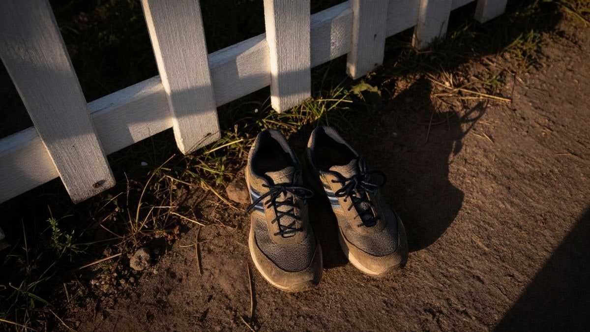 Imagen ilustrativa: vista cenital de unas zapatillas de running sobre un camino de tierra junto a una valla blanca al amanecer