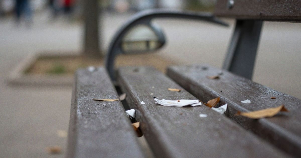 Imagen ilustrativa: primer plano de un banco de parque con basura y hojas secas, farola rota al fondo